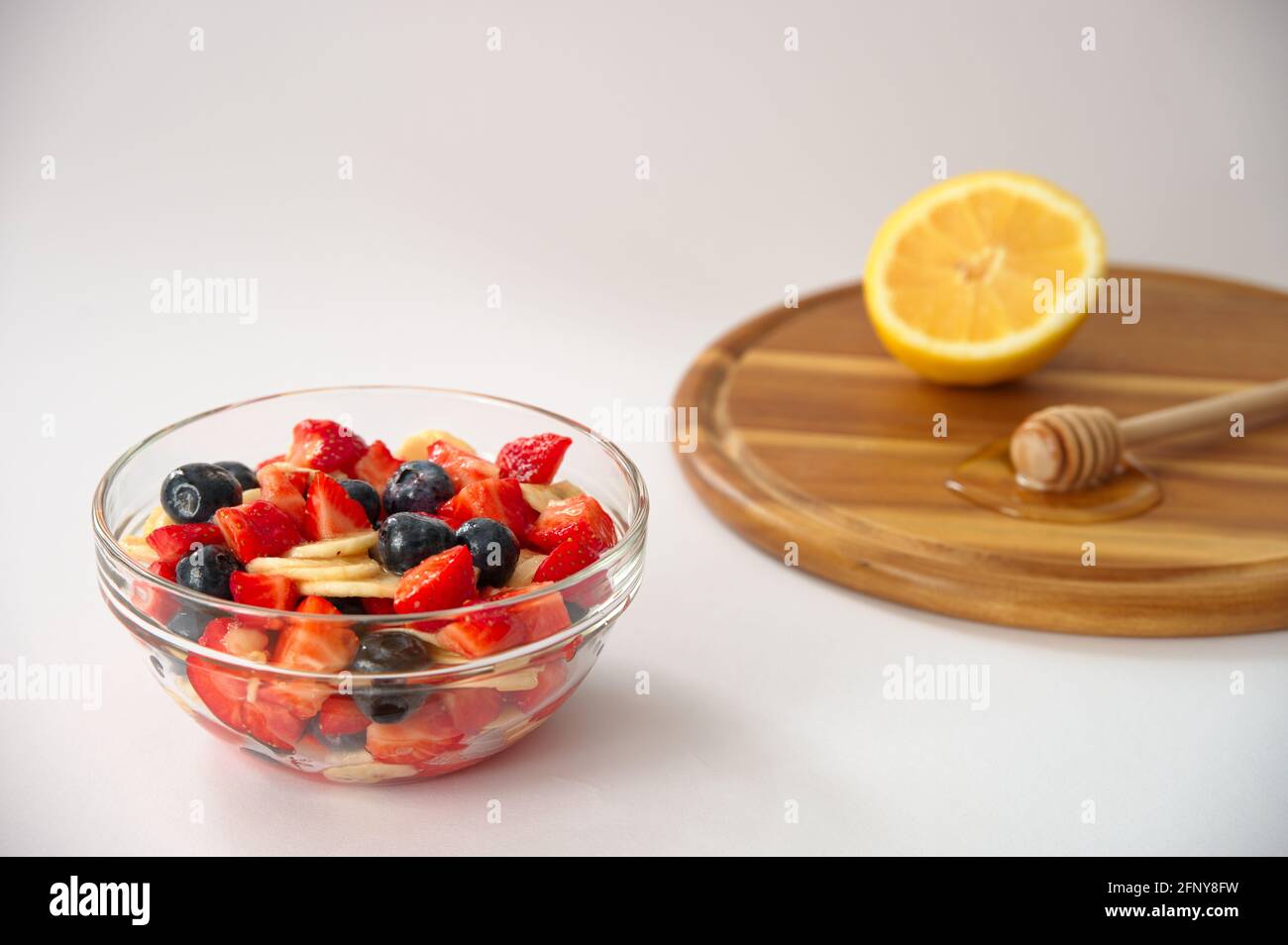 Healthy berry fruits with honey and lemon on white background Stock
