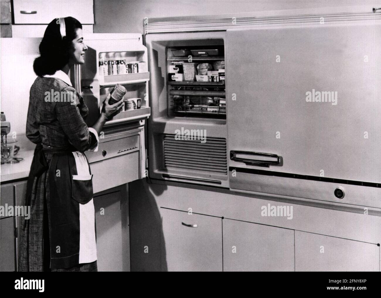 household, kitchen and kitchenware, housewife taking tin out of his refrigerator, 1950s, ADDITIONAL-RIGHTS-CLEARANCE-INFO-NOT-AVAILABLE Stock Photo