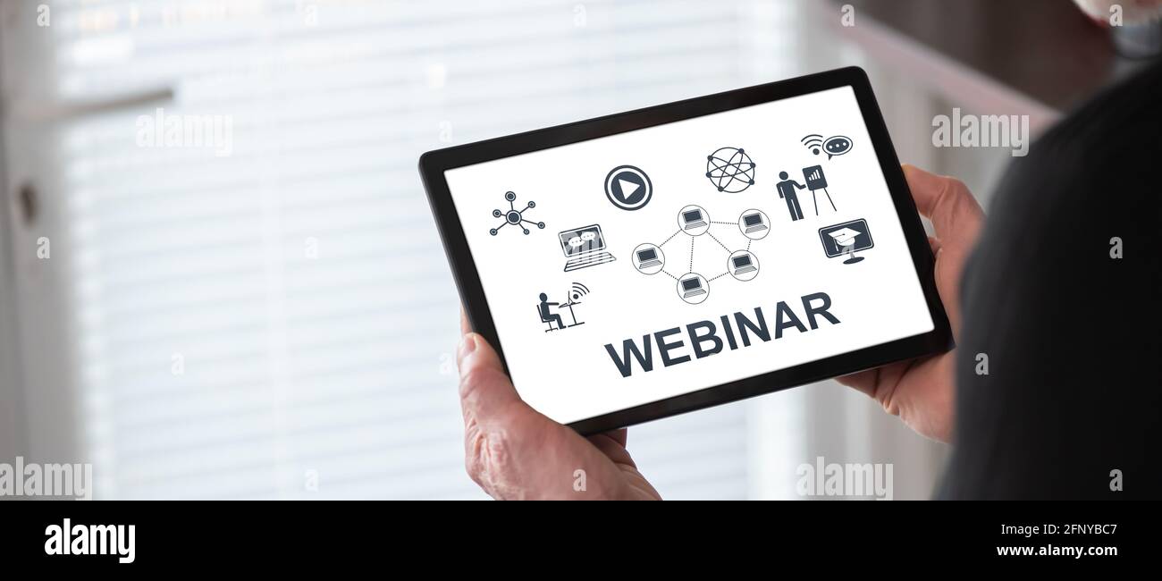 Webinar concept shown on a tablet held by a man Stock Photo