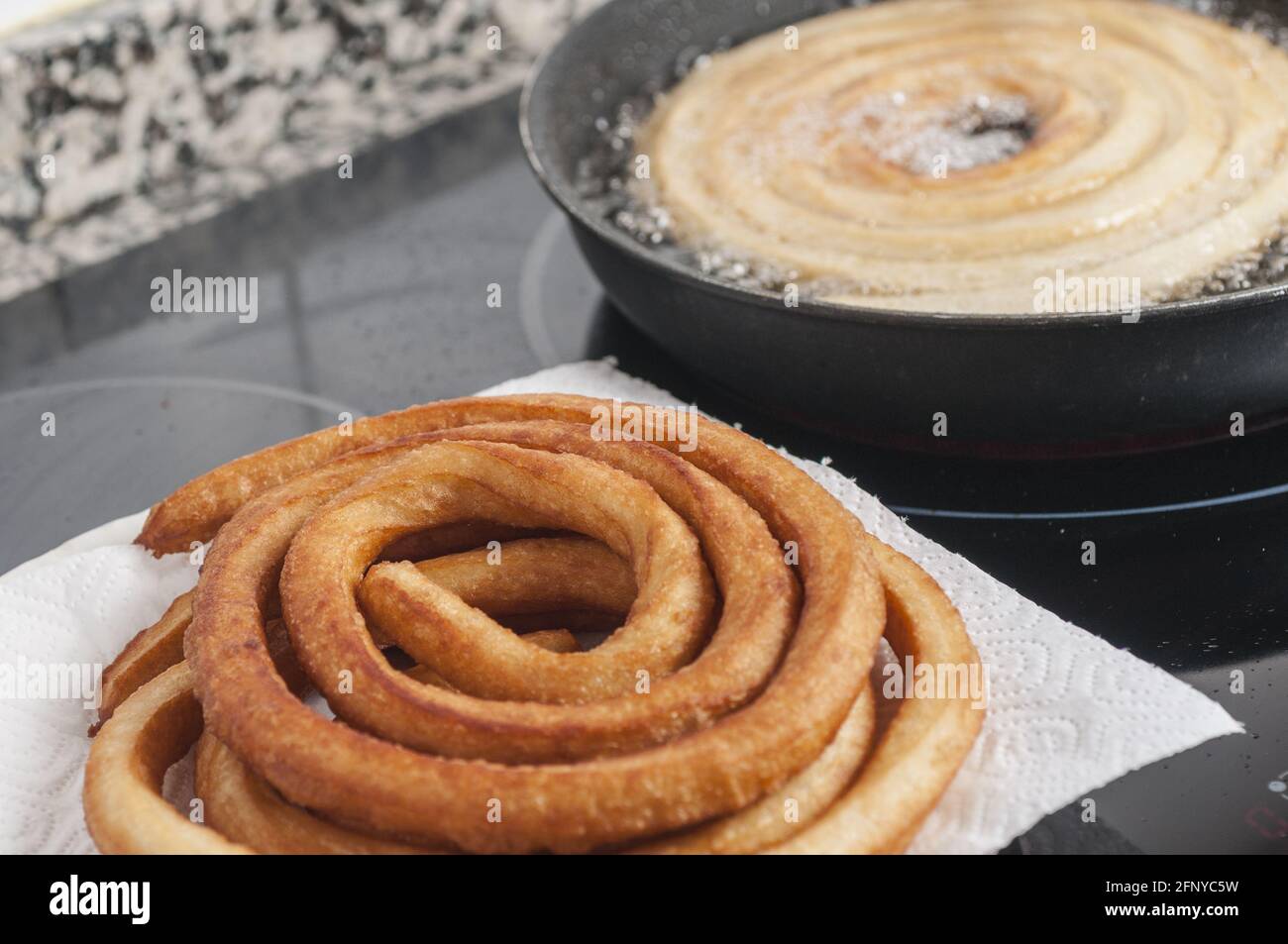 Closeup shot of freshly cooked churros at home on a white paper towel and frier Stock Photo