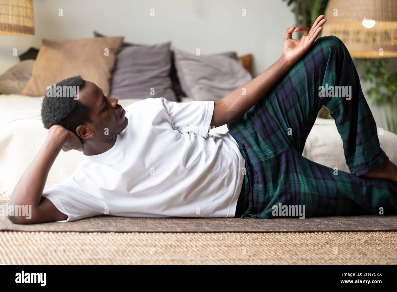 African yoga man doing anantasana pose working out at home Stock Photo