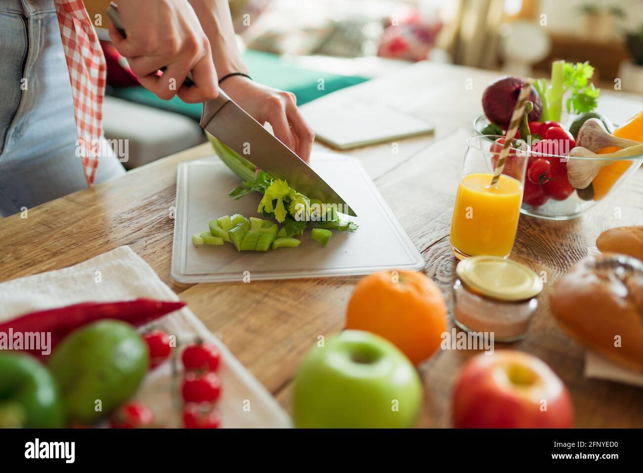 Close-up of the hand only view of a woman slicing a salad, preparing for a healthy organic vegetarian meal with chilli peppers and broccoli. On the Stock Photo