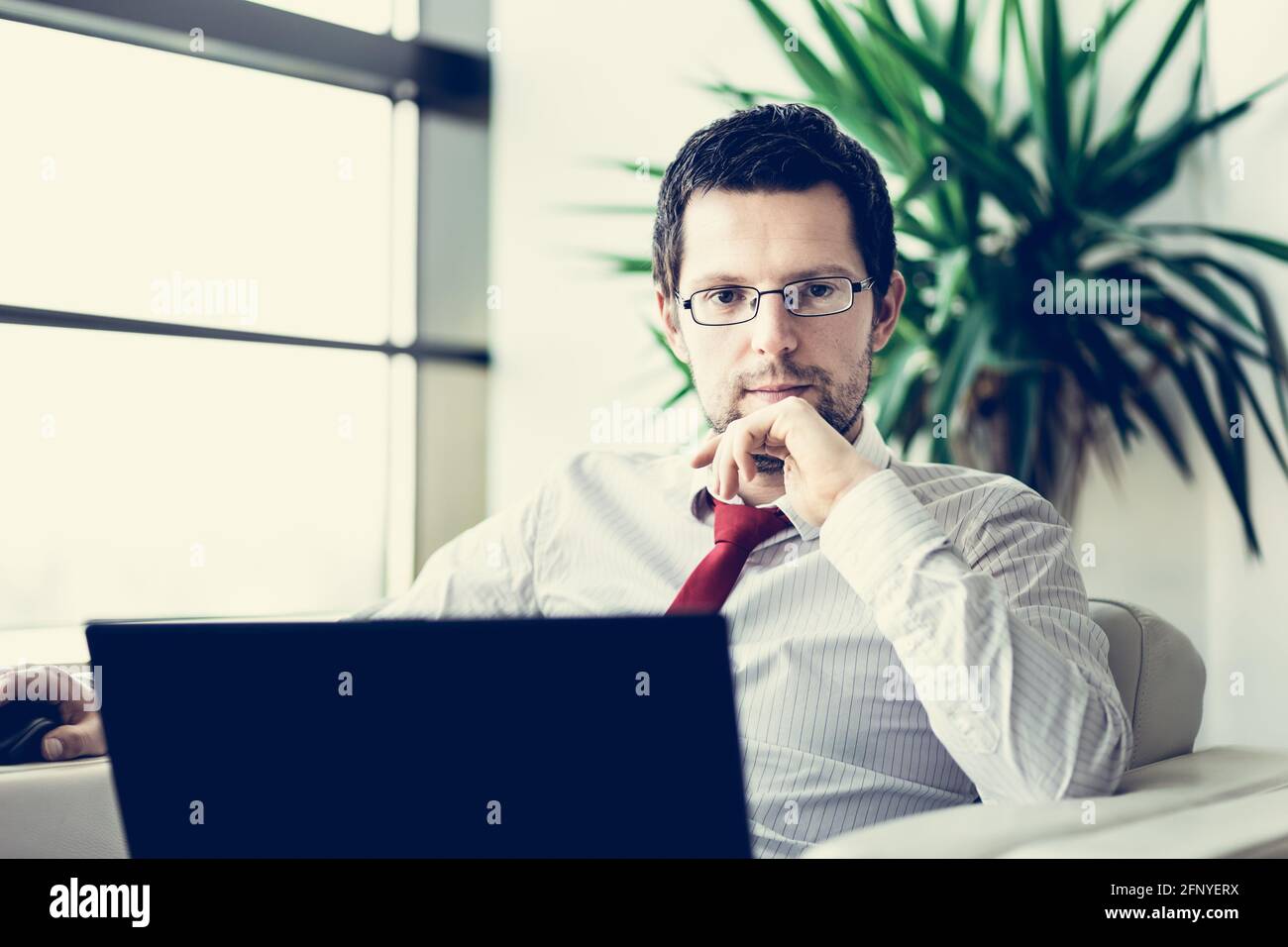 Portrait of businessman working on laptop computer Stock Photo