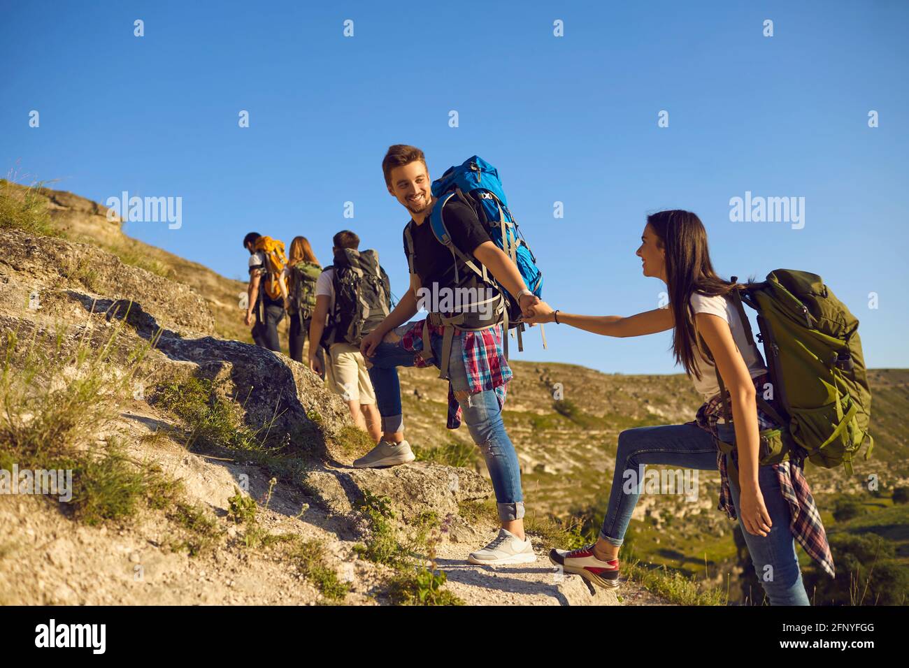 Group of tourists on hiking trip in mountains. Team of active young people with backpacks mountaineering outdoors Stock Photo