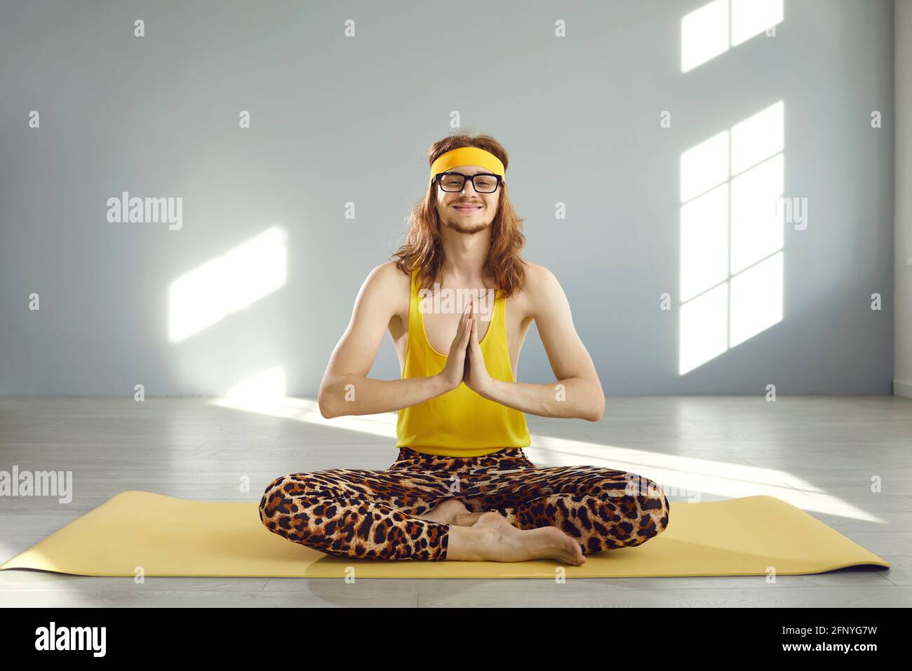 Funny calm man enjoying yoga meditation exercise sitting legs crossed on fitness mat Stock Photo
