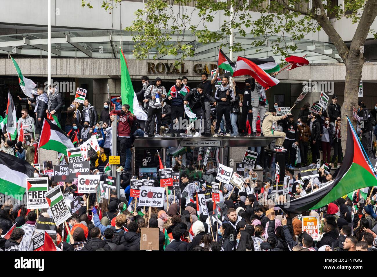 Protesters wave flags from roof of bus shelter, 'Free Palestine' solidarity protest, London, 15 May 2021 Stock Photo