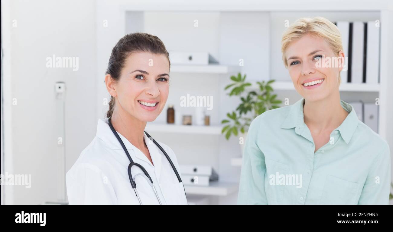 Portrait of caucasian female doctor and female patient smiling at hospital Stock Photo