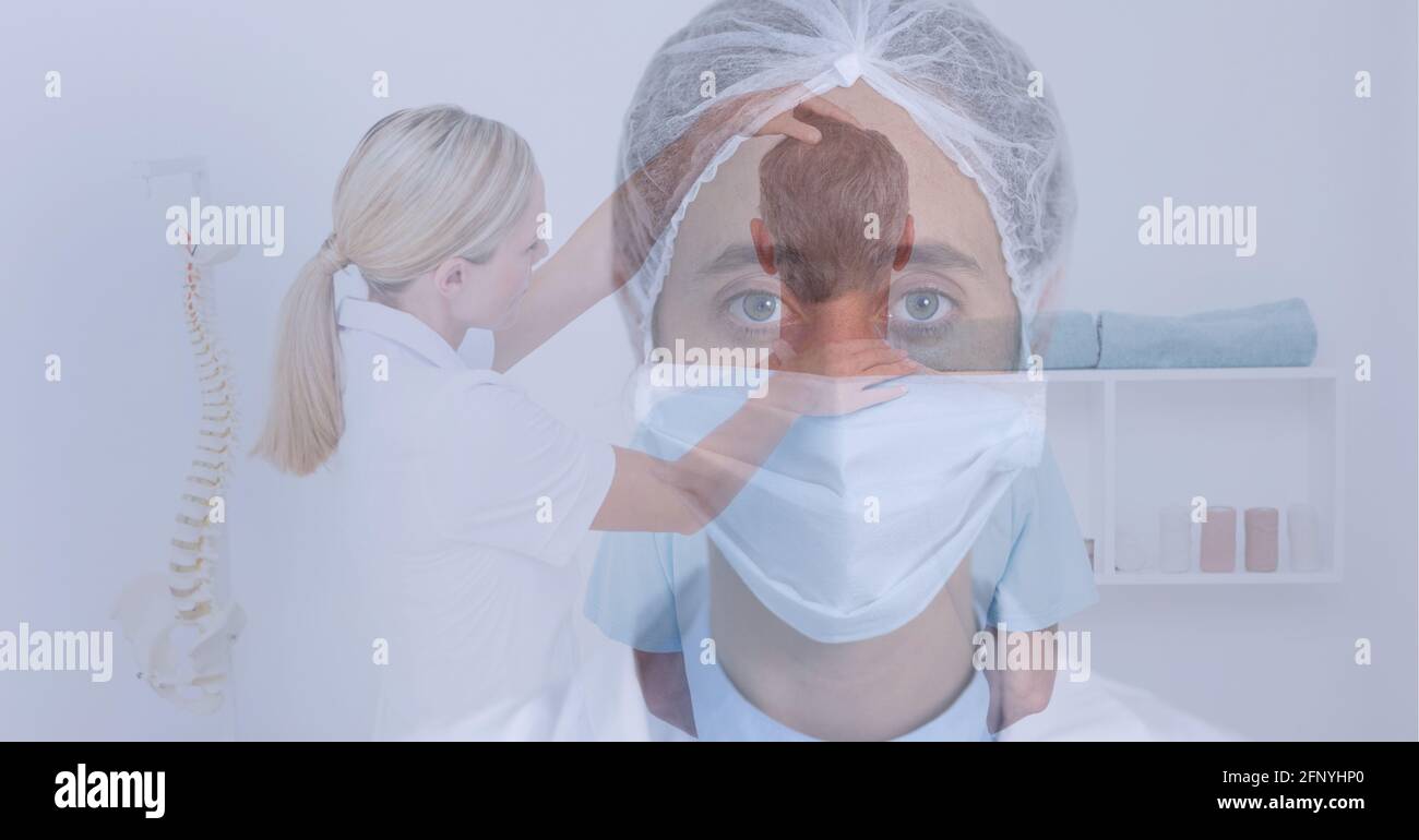 Caucasian female doctor wearing facemask against female doctor examining neck of male patient Stock Photo