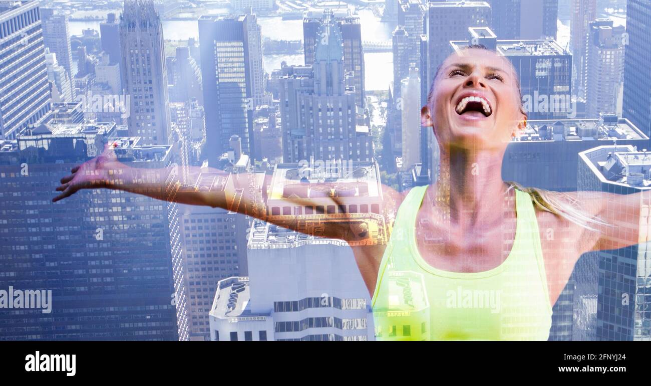 Composition of happy, healthy caucasian woman with arms outstretched over modern city background Stock Photo