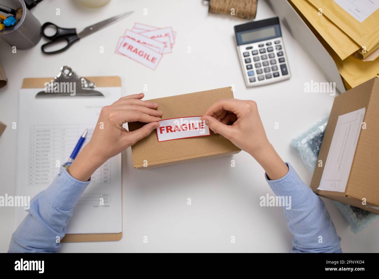 woman sticking fragile mark to parcel box Stock Photo