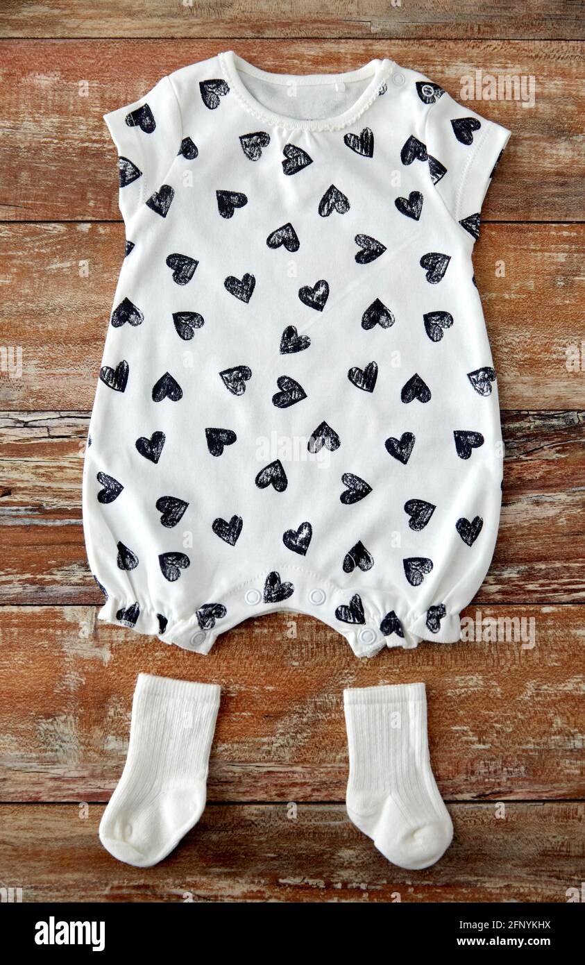 baby bodysuit and socks on wooden table Stock Photo