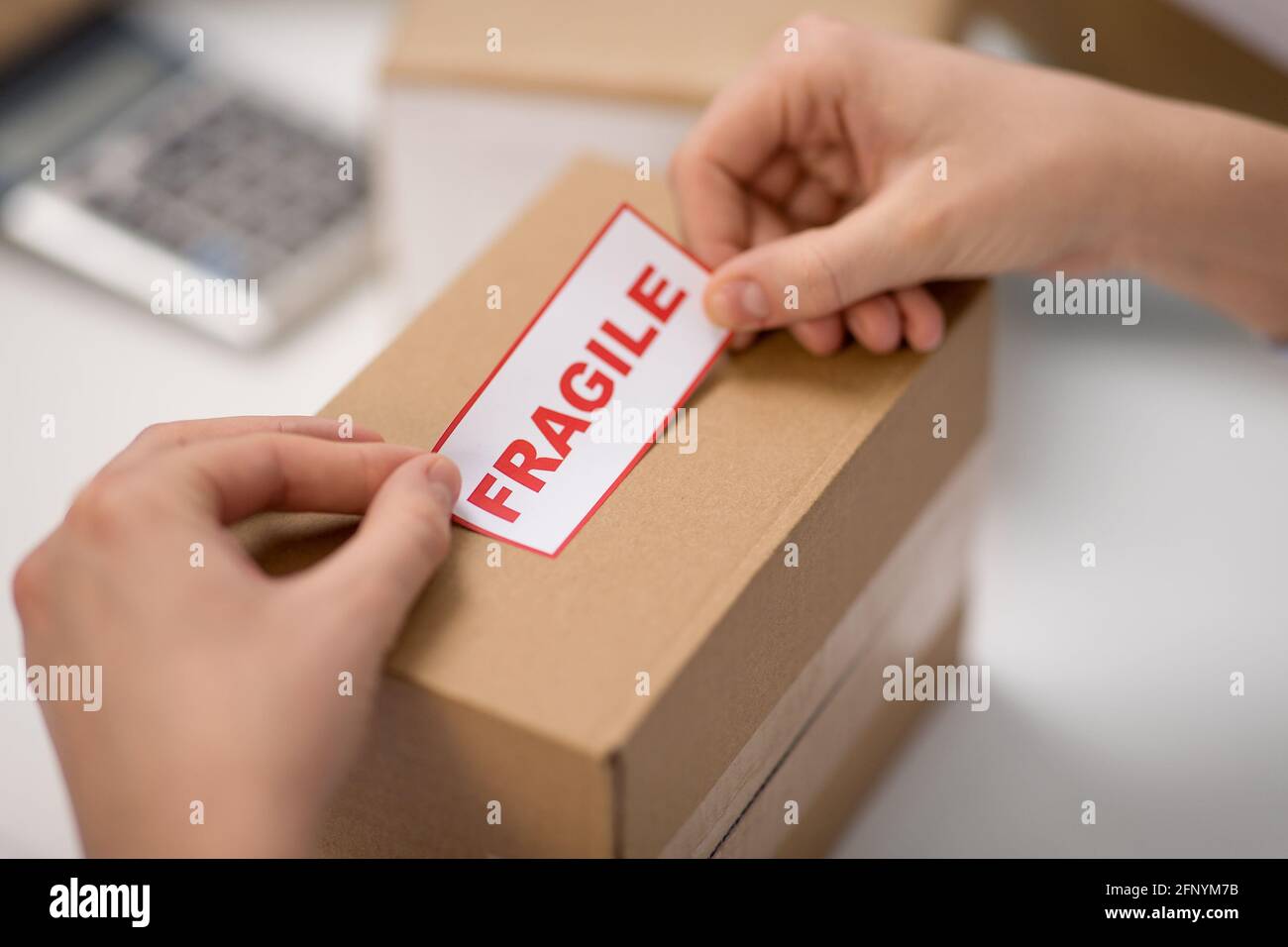 woman sticking fragile mark to parcel box Stock Photo