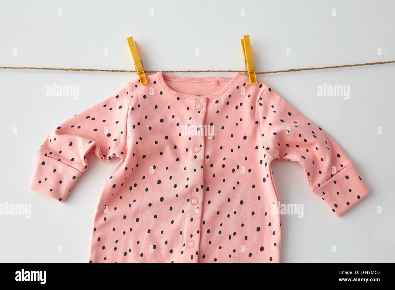 bodysuit for baby girl hanging on rope with pins Stock Photo
