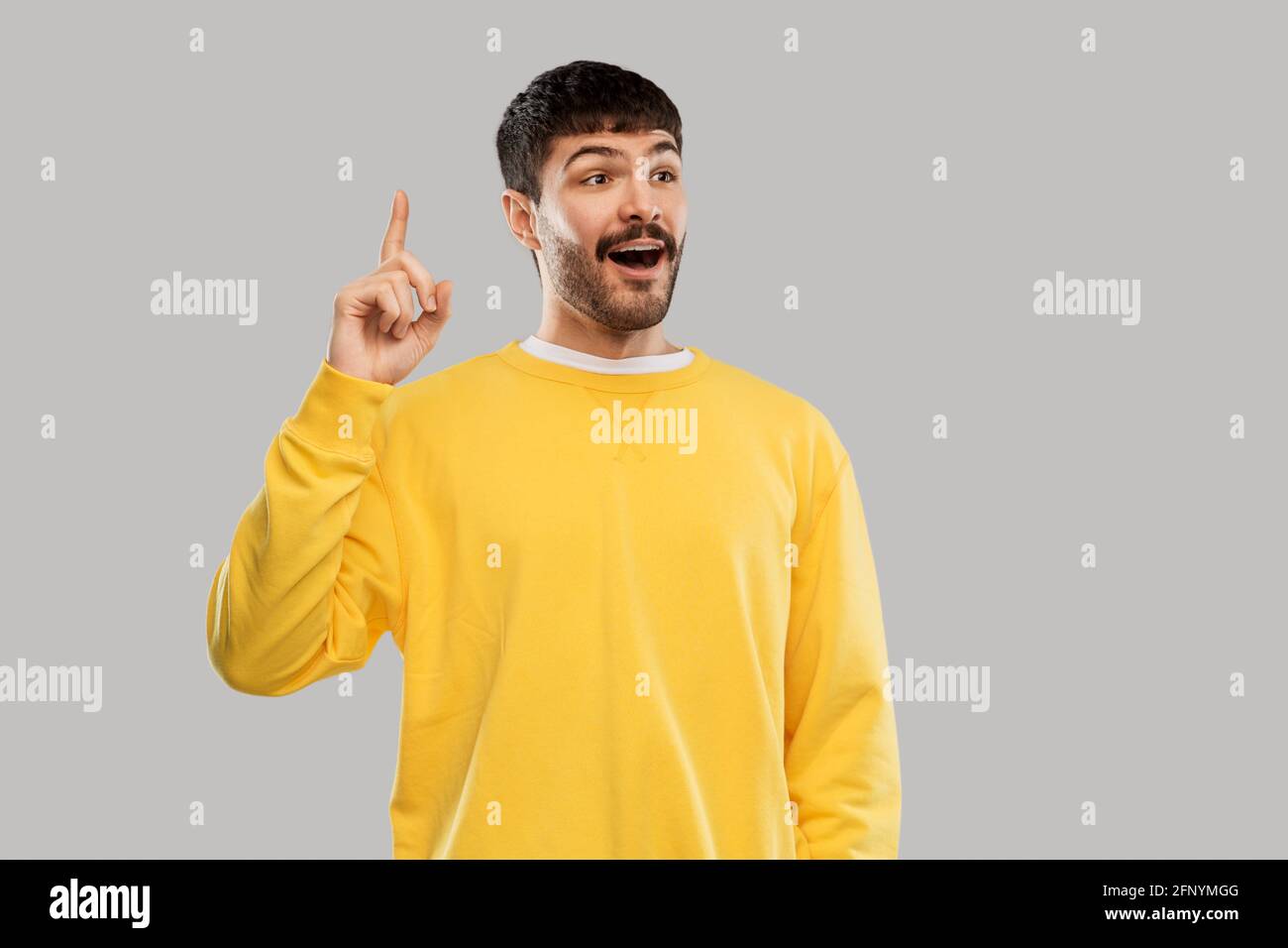 young man showing one finger in yellow sweatshirt Stock Photo