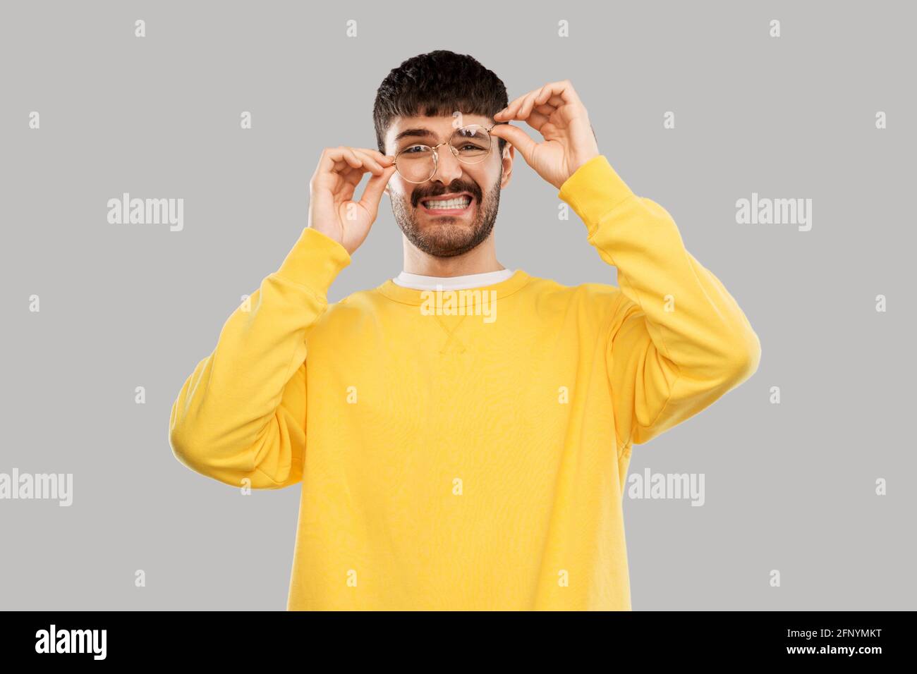 goofy young man in glasses and yellow sweatshirt Stock Photo