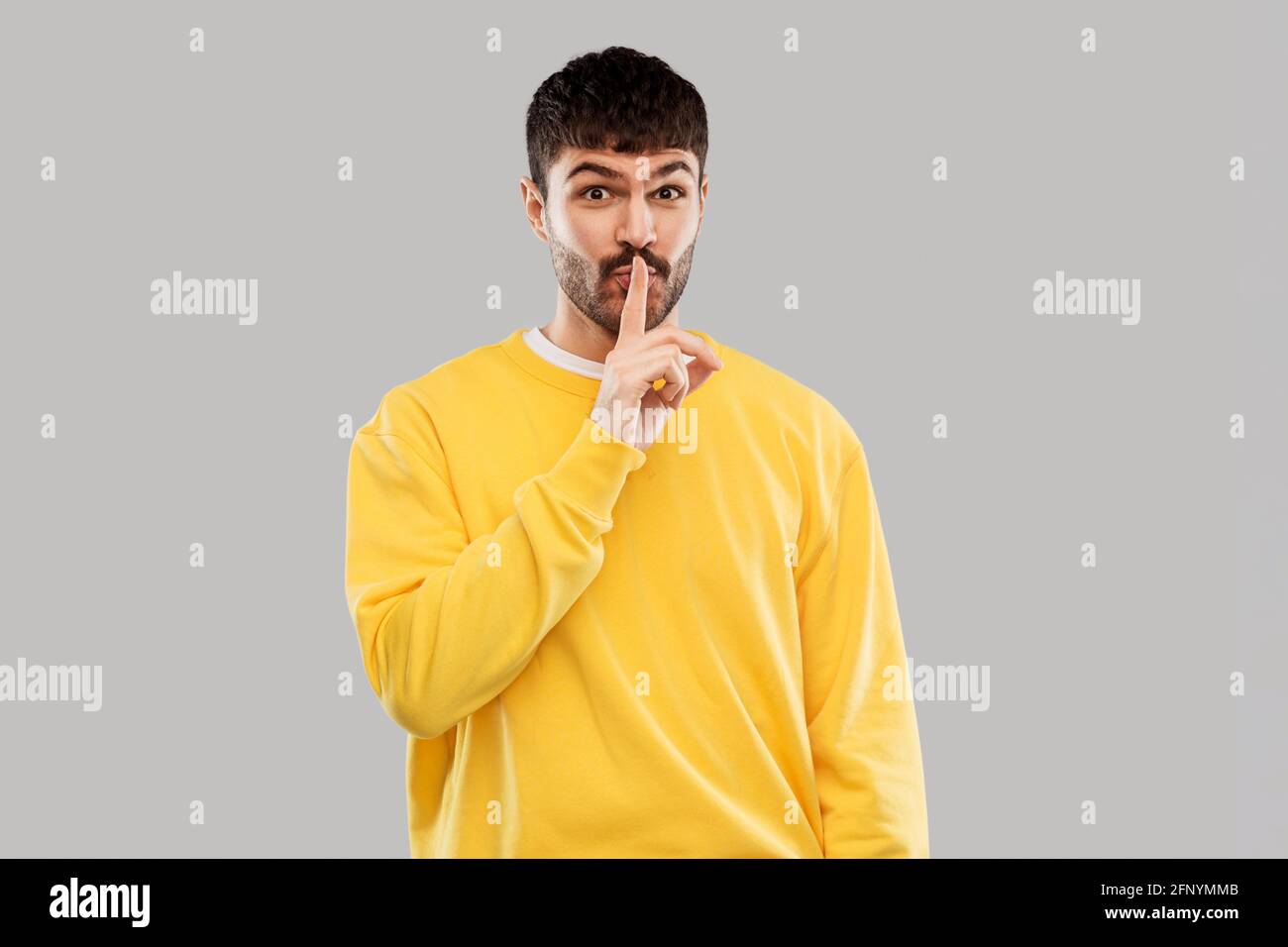 young man making hush gesture with finger on lips Stock Photo