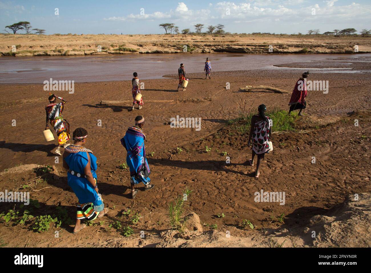 Women walk to collect water to a river near the village of Umoja in Samburu, Kenya on February 19, 2015. Stock Photo