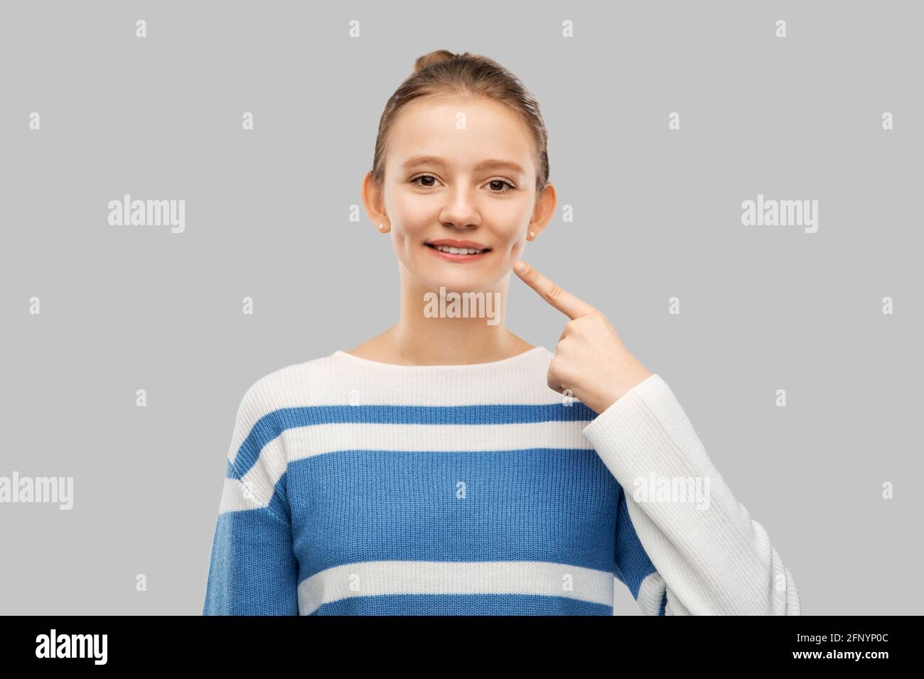 smiling teenage girl pointing finger to her face Stock Photo