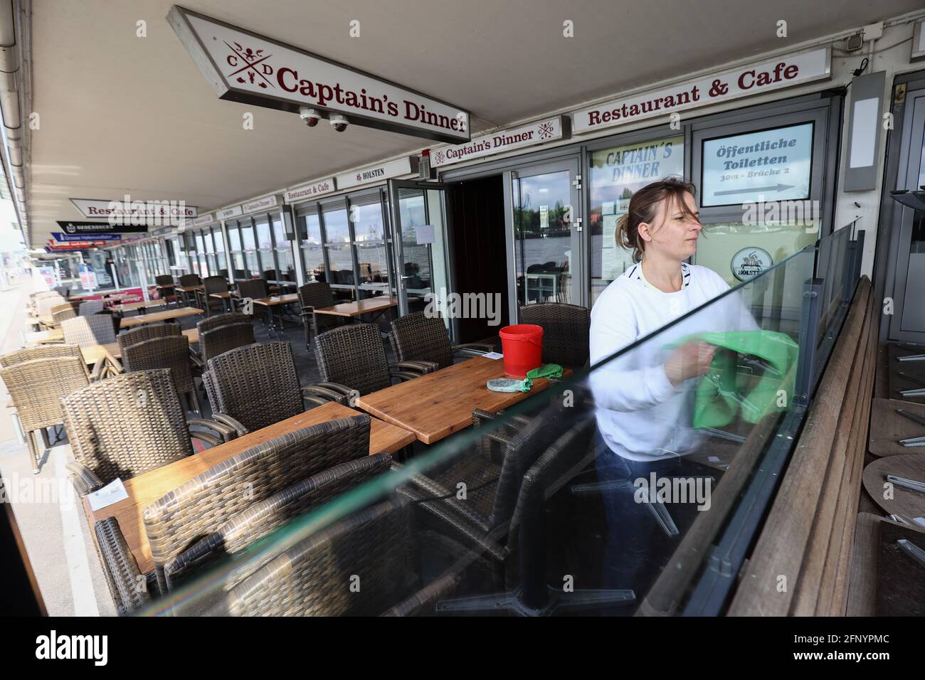 20 May 2021, Hamburg: Sandra Warncke, service manager at the Captain's Dinner restaurant, cleans the outdoor area of the restaurant on the Landungsbrücken. Just in time for Whitsun, outdoor restaurants, retail outlets and even outdoor swimming pools will be allowed to reopen from Saturday. Photo: Christian Charisius/dpa Stock Photo