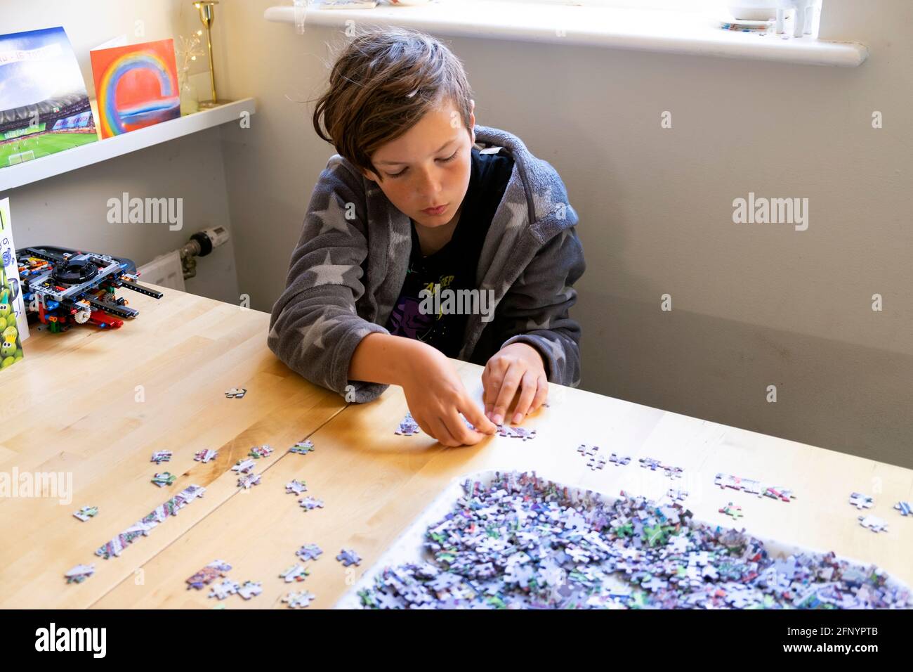 Boy 11 concentrating working on jigsaw puzzle on kitchen table at home during Covid 19 pandemic lockdown in 2021 UK Great Britain   KATHY DEWITT Stock Photo