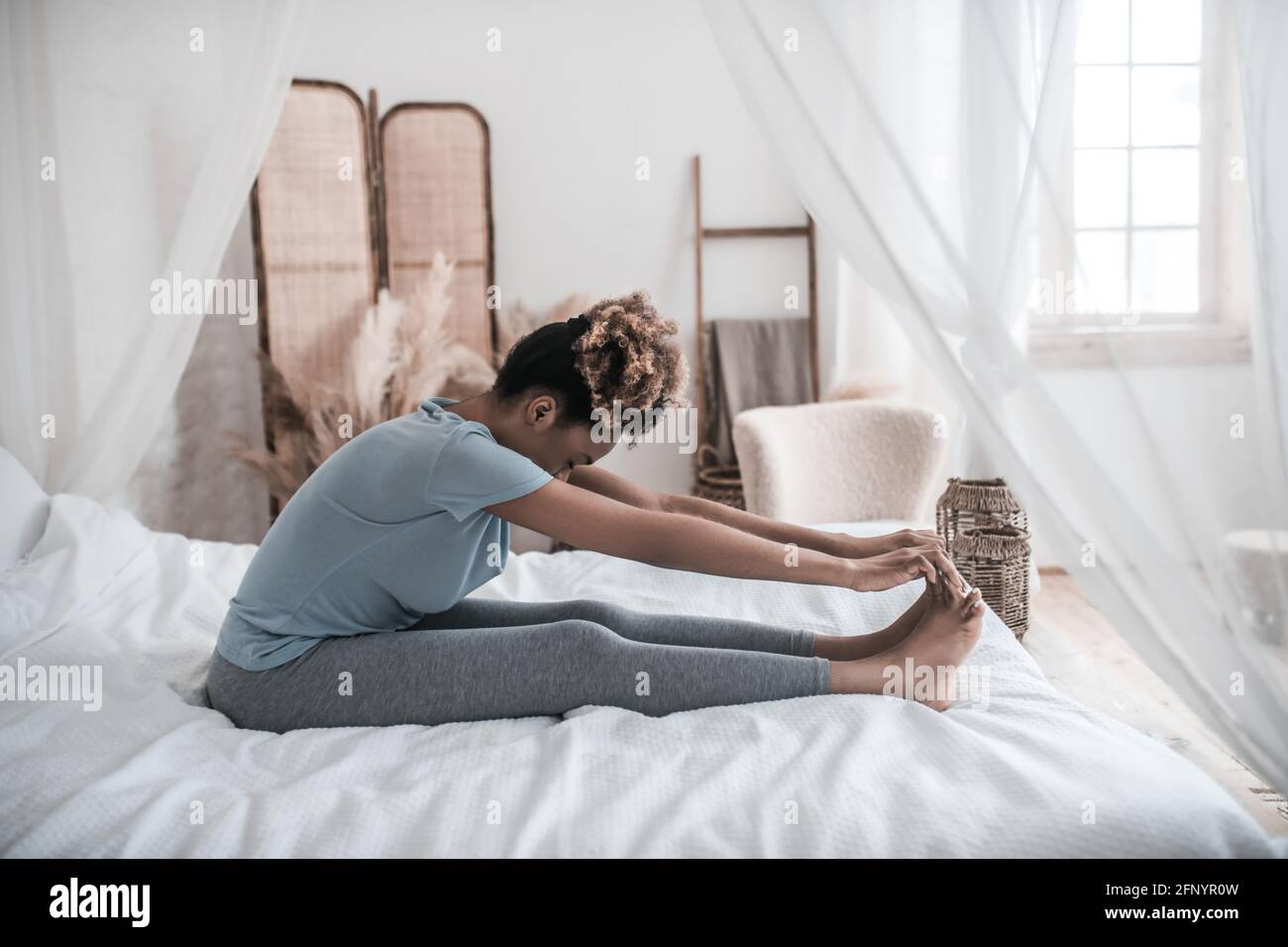 Woman sitting on bed with head bowed to feet Stock Photo Alamy