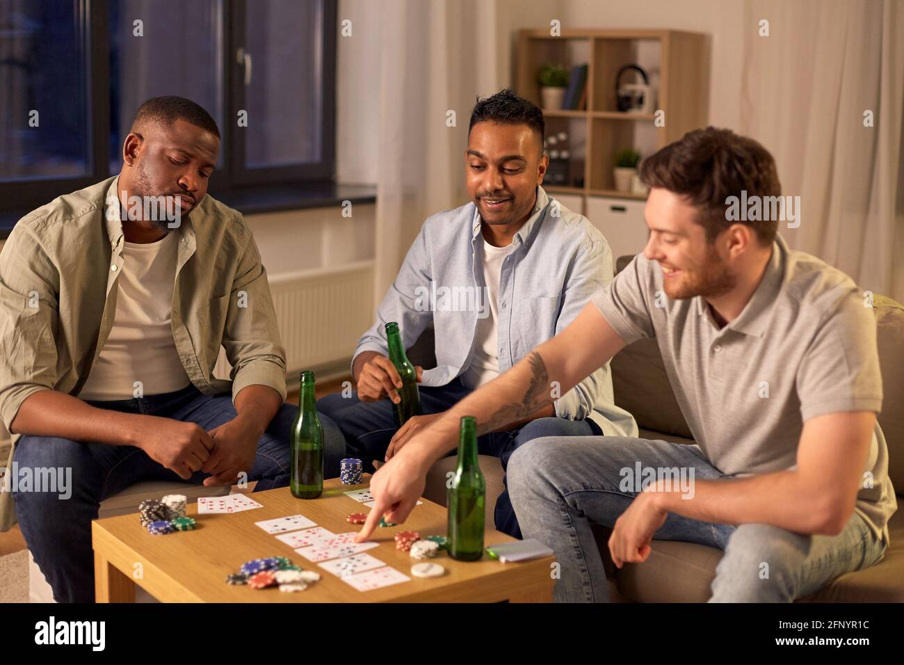 smiling male friends playing cards at home Stock Photo