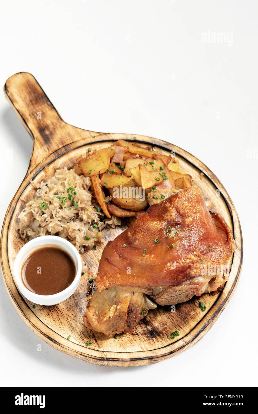 SCHWEINSHAXE traditional german pork knuckle with sauerkraut and potatoes meal on white background Stock Photo