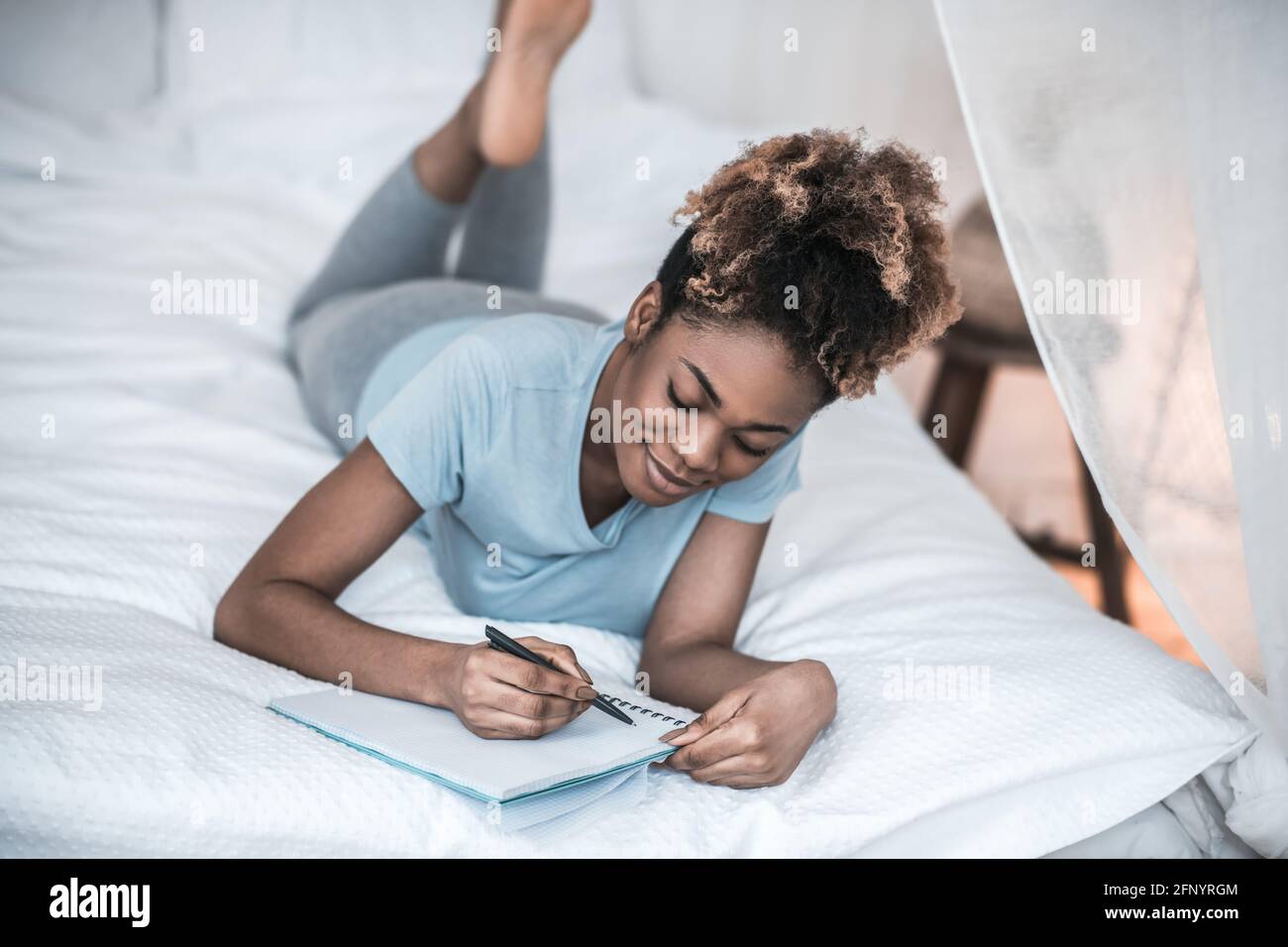 Involved woman lying on bed writing in notebook Stock Photo Alamy