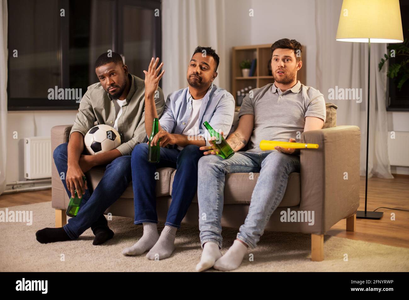 sad friends with ball and vuvuzela watching soccer Stock Photo