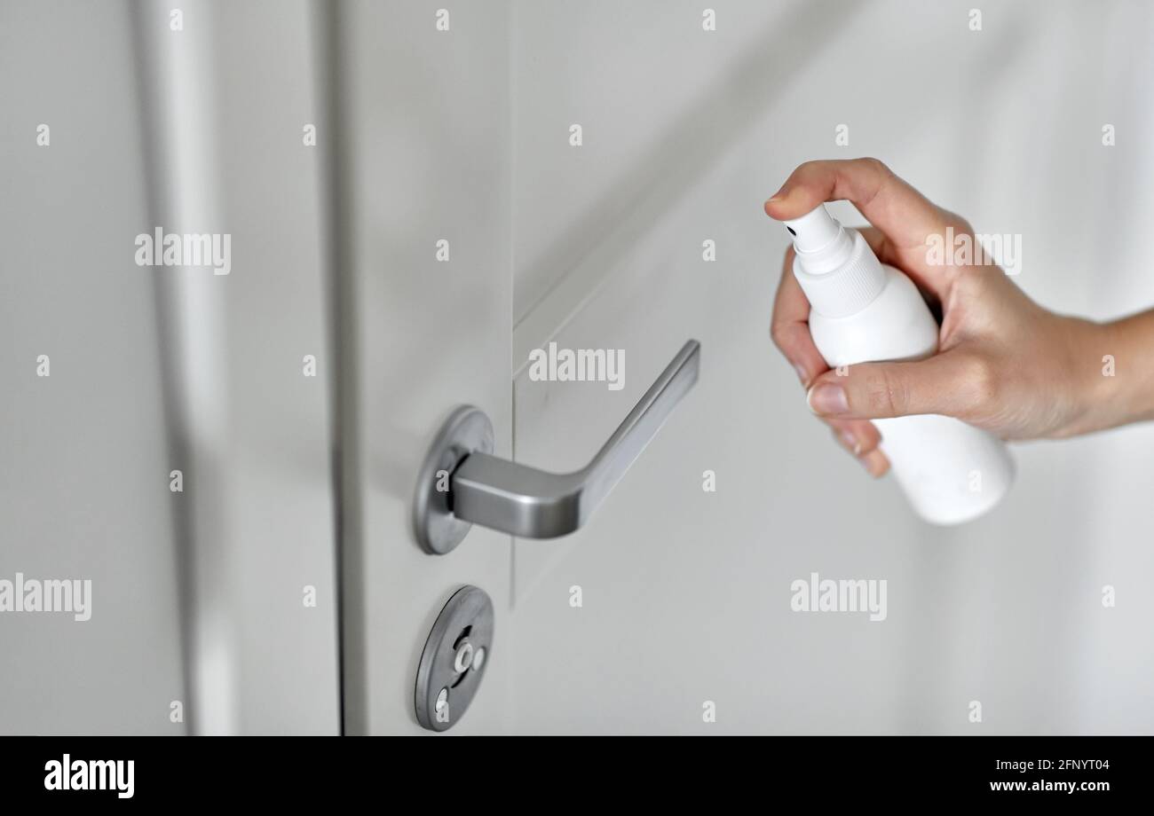 hand spaying disinfectant to door handle surface Stock Photo
