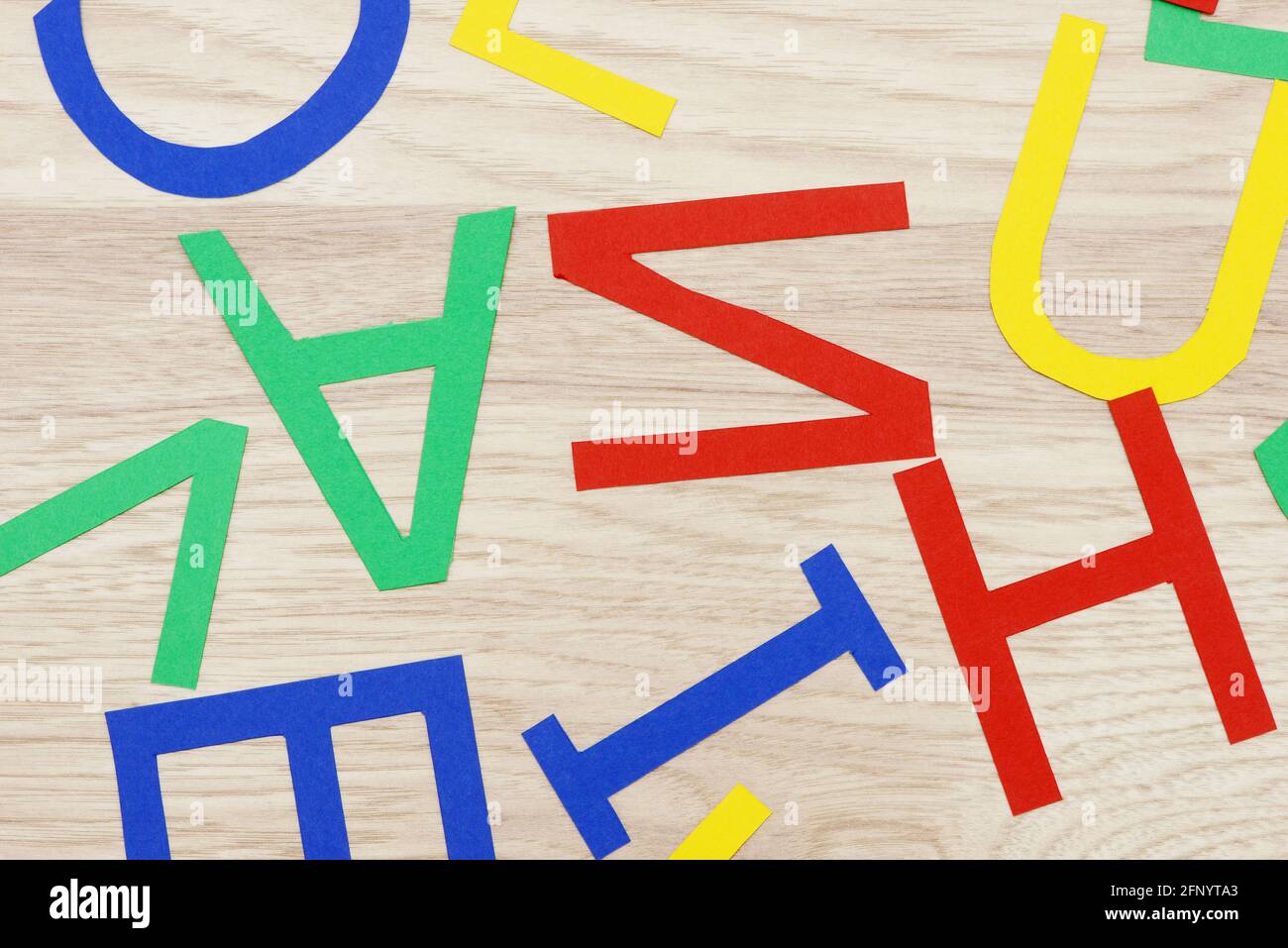 colorful jumbled letters, made of paper,  lying on wood Stock Photo