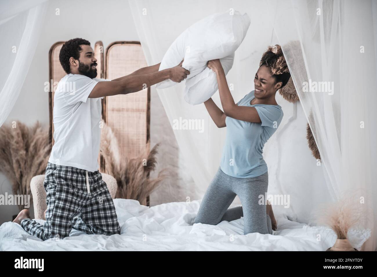 Husband and wife fighting pillows on bed Stock Photo Alamy