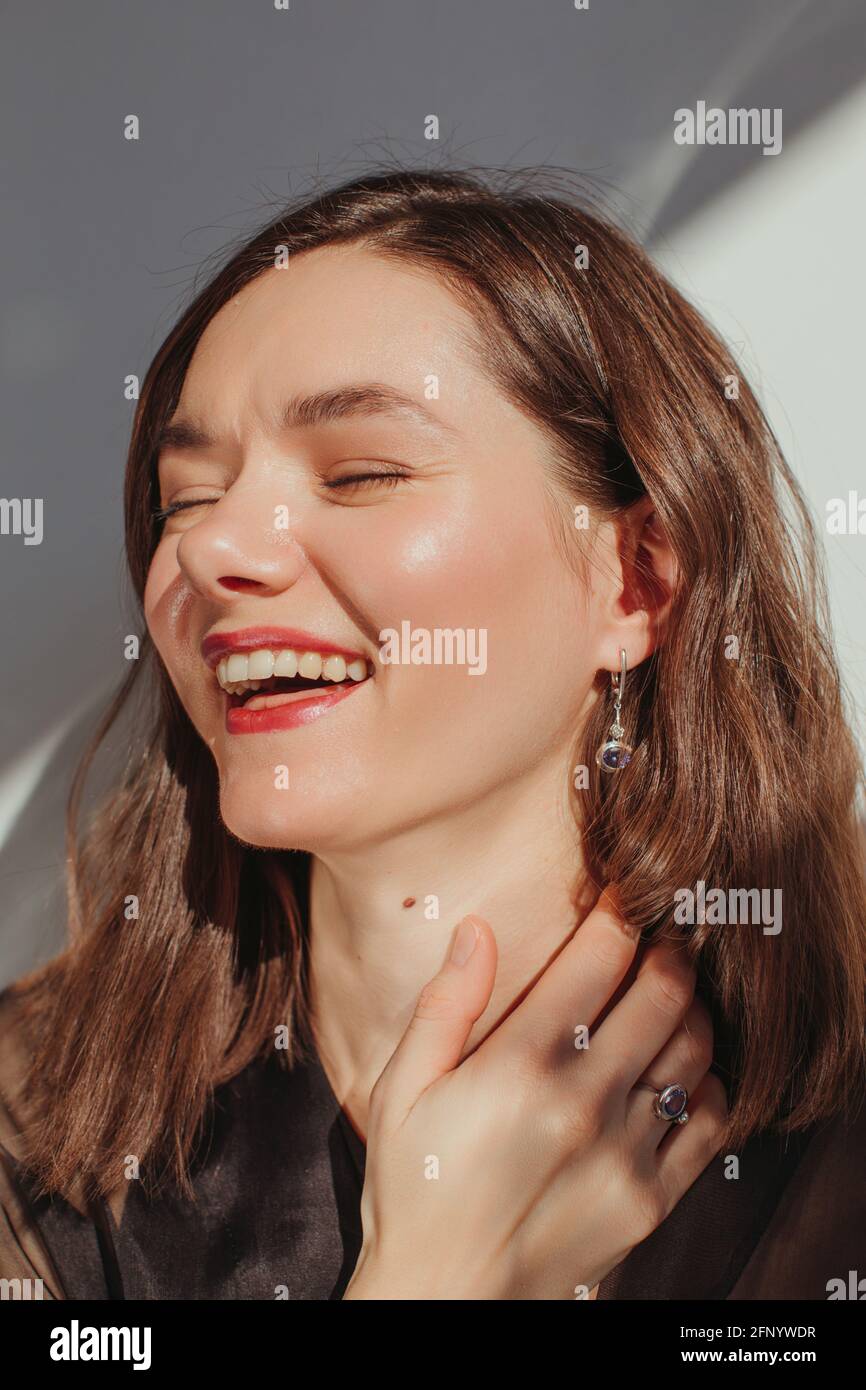 Portrait of a beautiful with her hand on her neck laughing Stock Photo