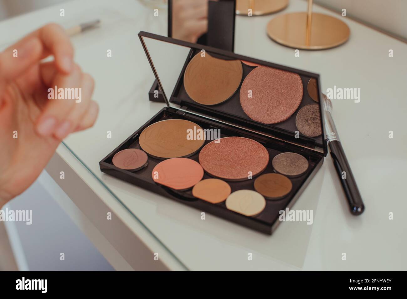 Close-up of a woman's hand reaching for a make-up palette on a dressing table Stock Photo