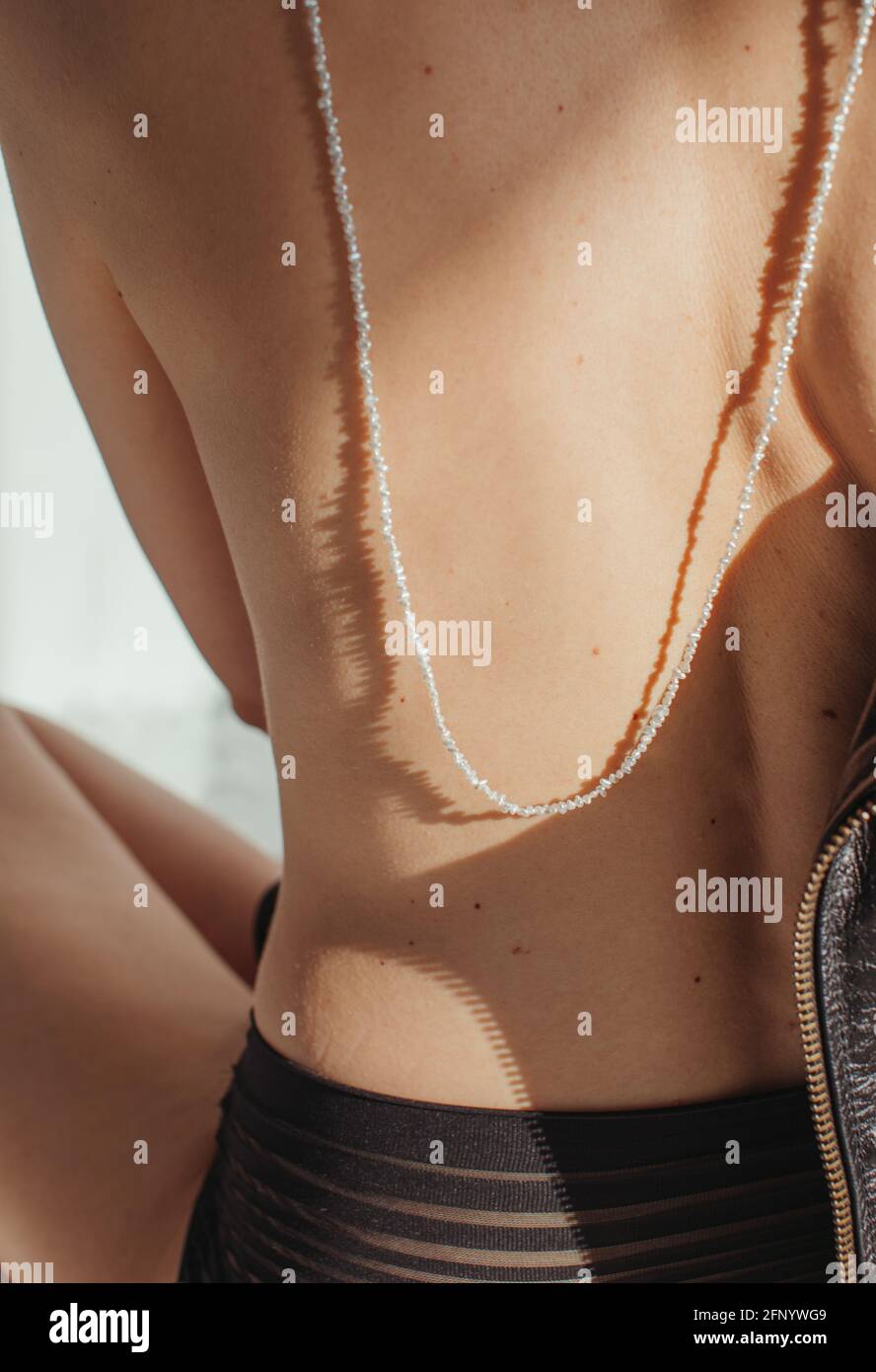 Rear view of a woman in lingerie wearing a necklace down her bare back Stock Photo
