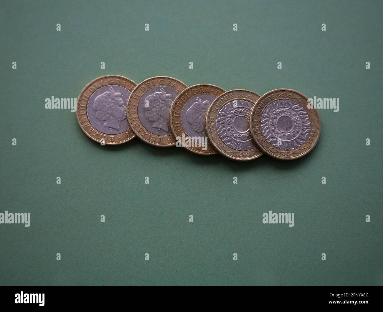 Close up five  British Sterling £2 coins on green background Stock Photo