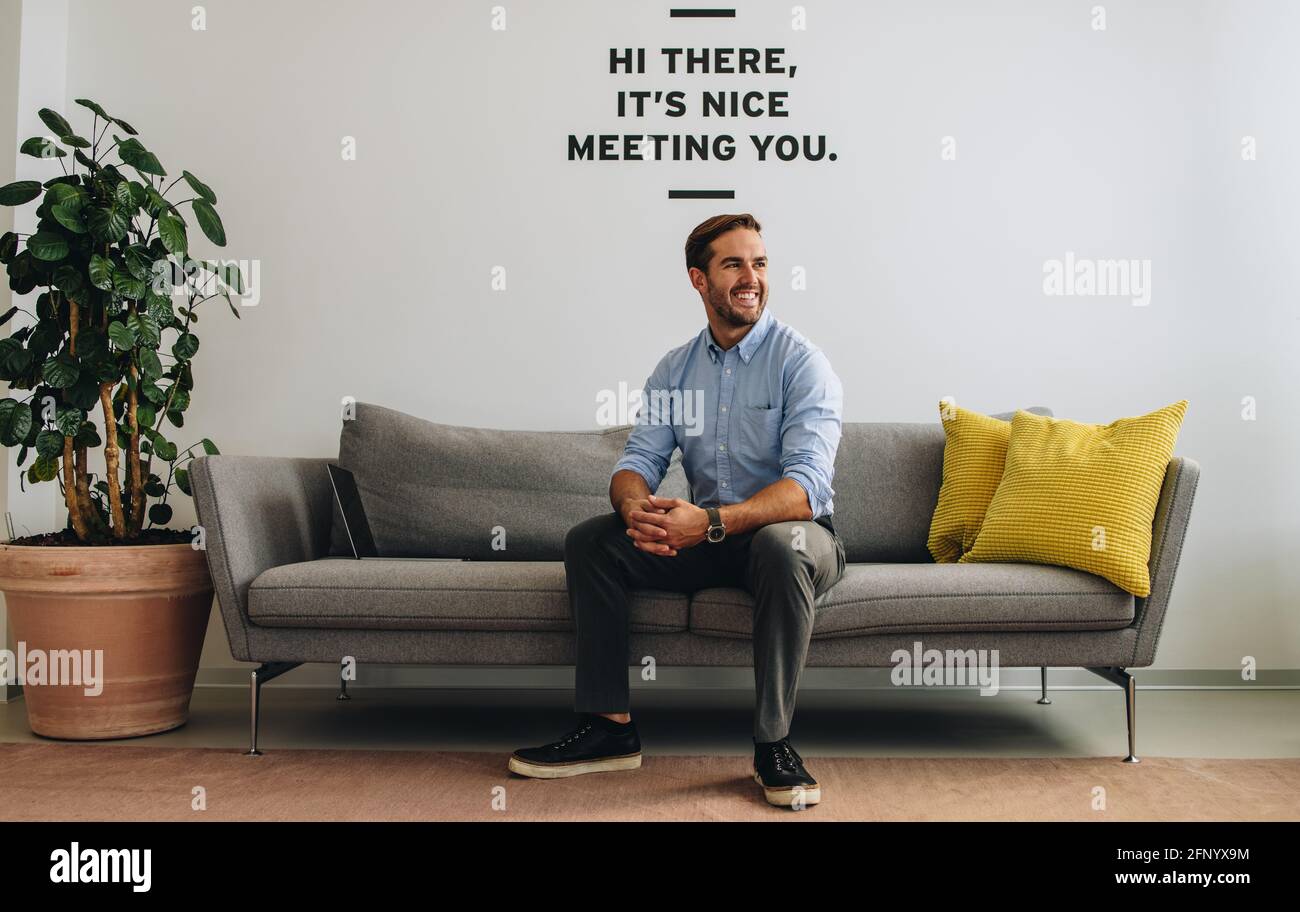 Confident freelancer sitting on sofa. businessman sitting and looking away in lobby. Stock Photo