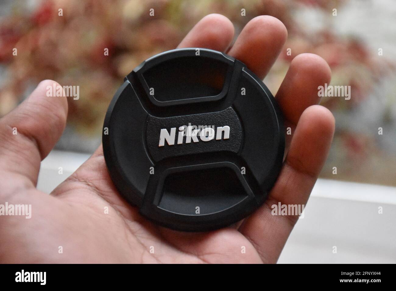 a nikon lens cap on a hand Stock Photo