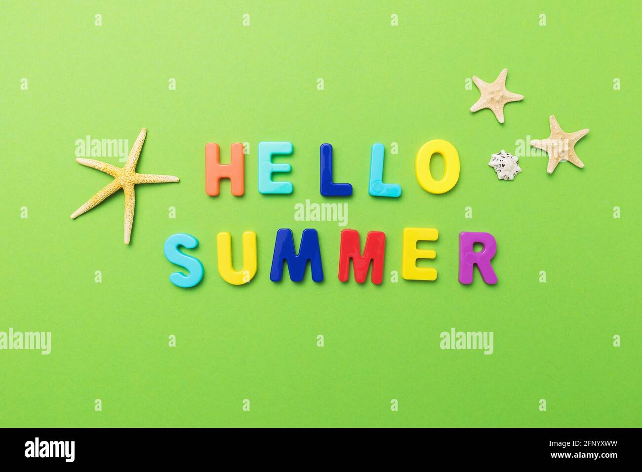 The inscription from multi-colored plastic letters with starfish on a green background. Stock Photo