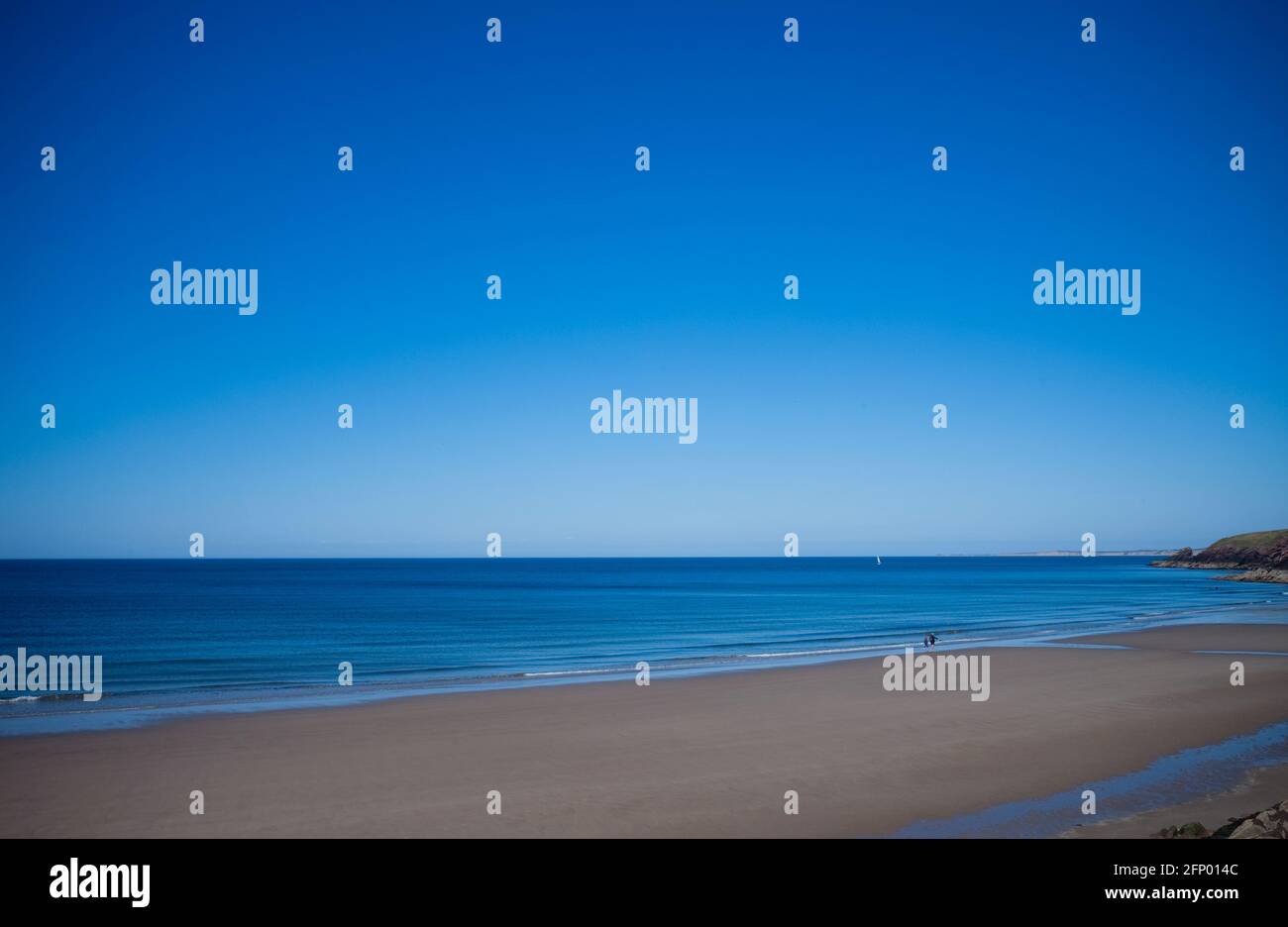 The ultra blue sea and sky at Peel beach on the west coast of the Isle of  Man with distant people walking at the waters edge Stock Photo - Alamy