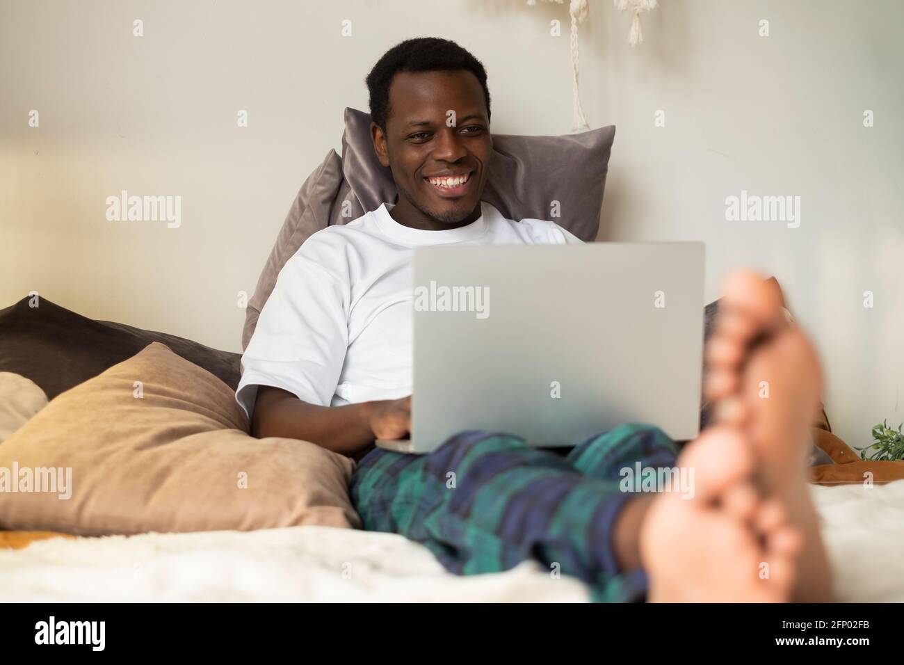 African man surfing the internet in his bed at home Stock Photo