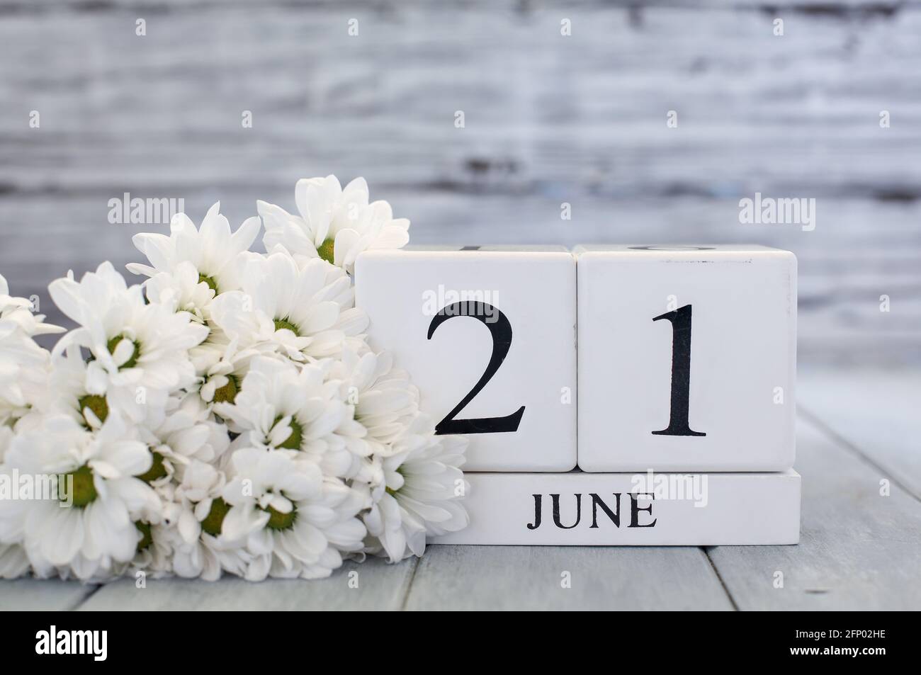 Summer Solstice White wood calendar blocks with the date June 21st  and white daisies. Selective focus with blurred background. Stock Photo