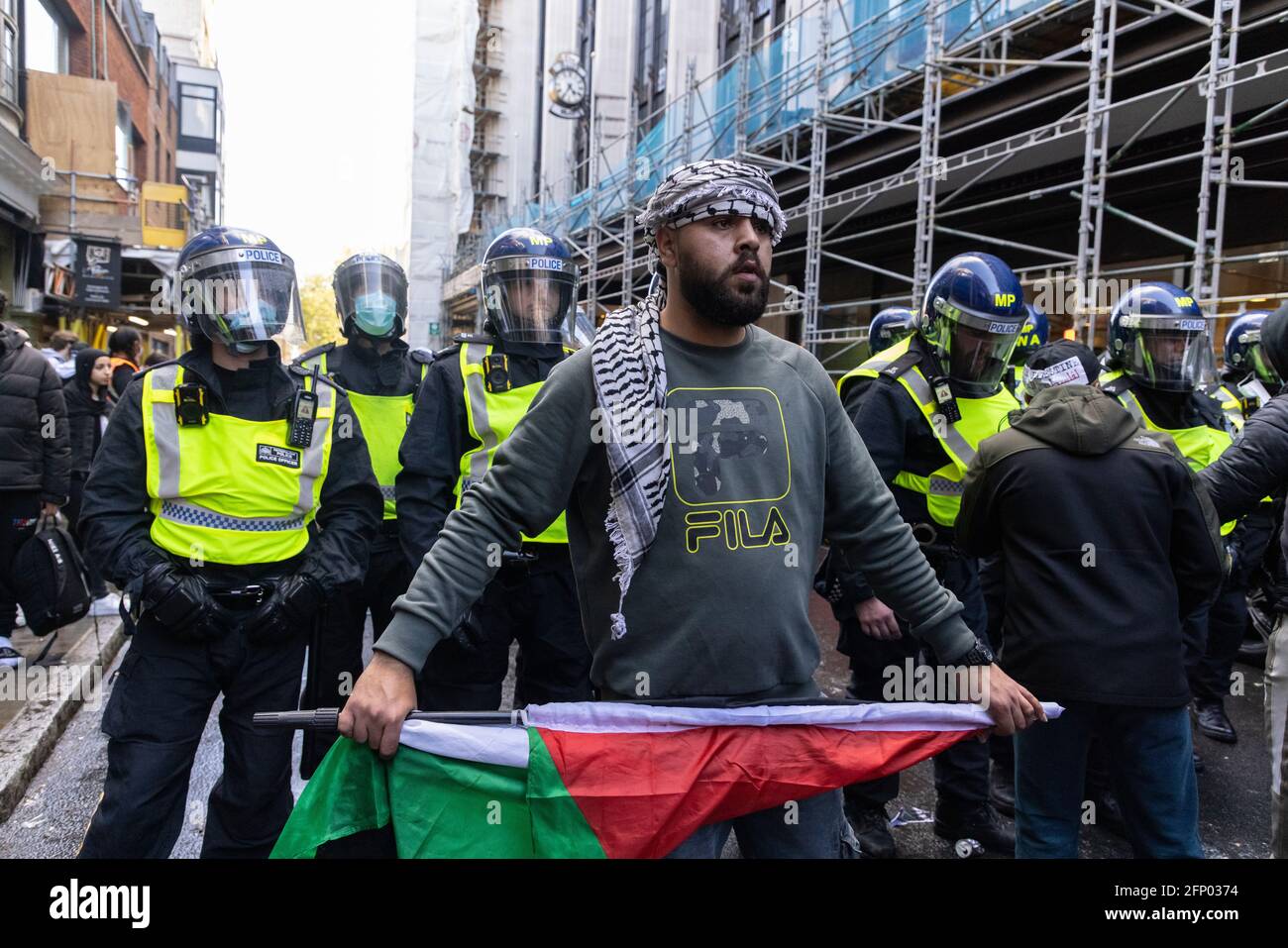 Protester with palestinian flag stands in front of police, 'Free Palestine' solidarity protest, London, 15 May 2021 Stock Photo