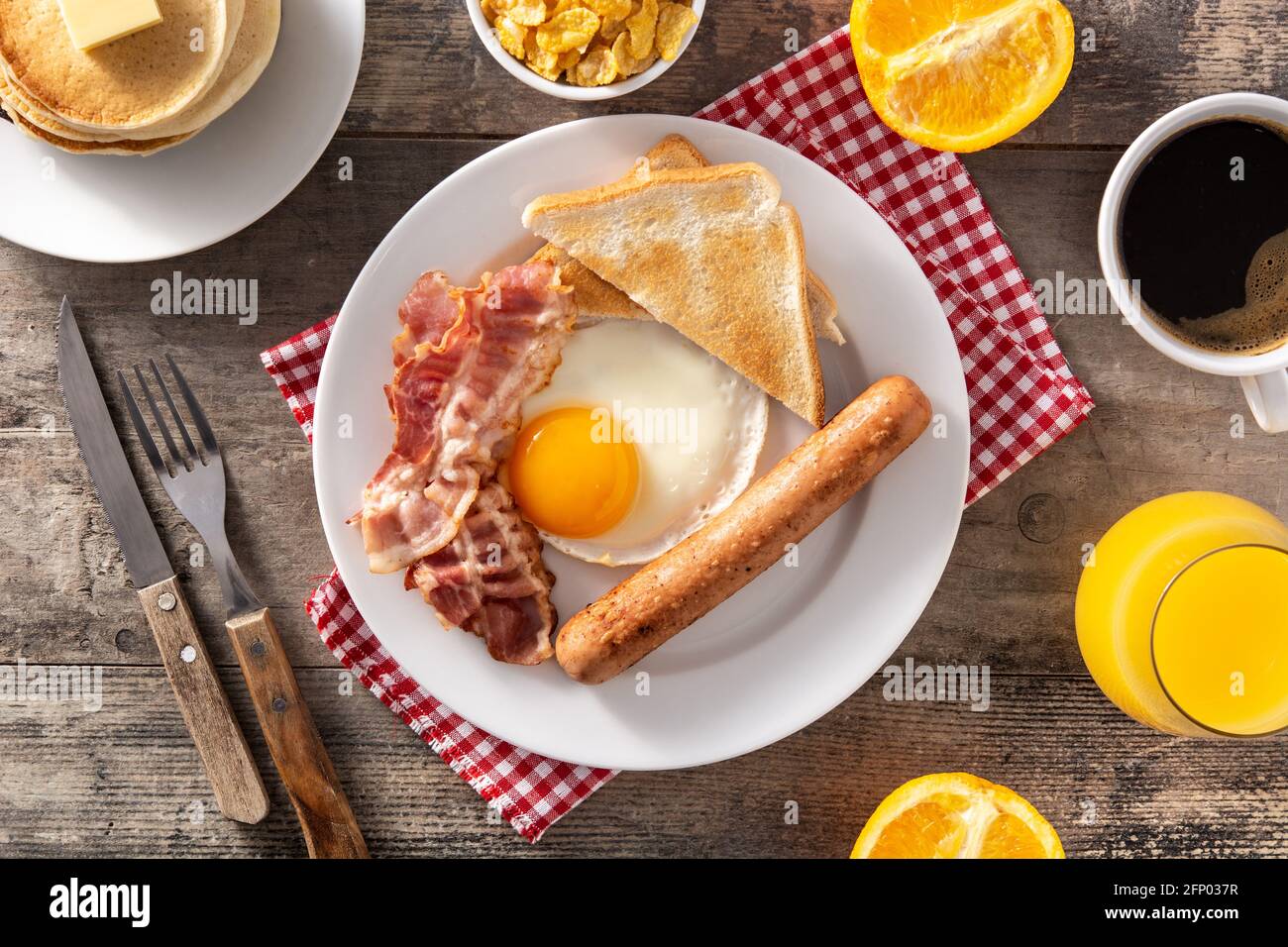 Traditional American breakfast with fried egg,toast,bacon and sausage on wooden table Stock Photo