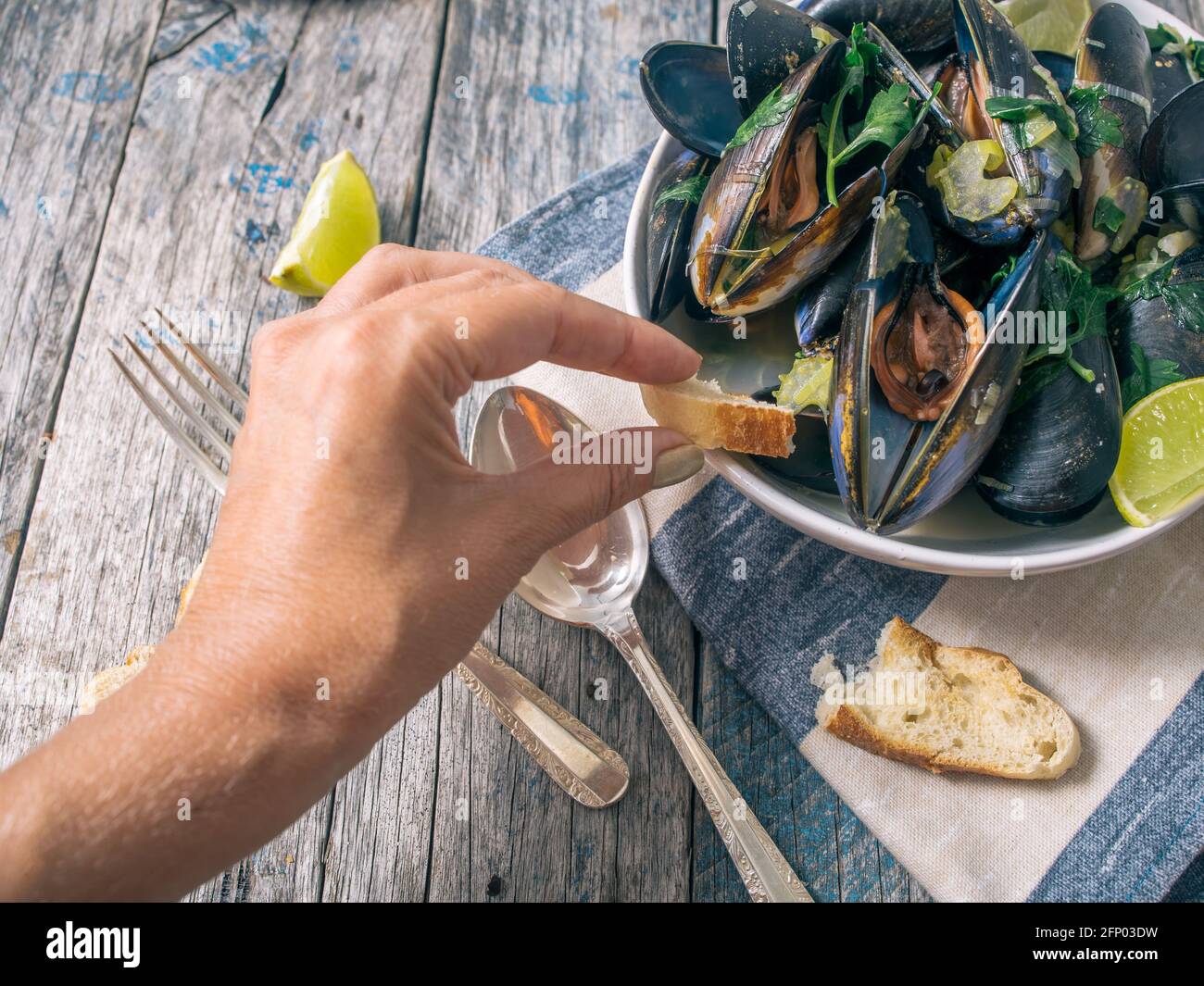 Blue mussles with vine and baguette on wooden table Stock Photo
