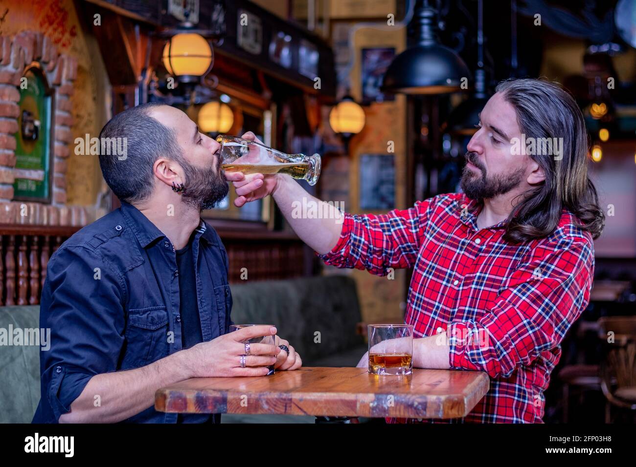 Two male friends drinking whiskey and beer together at the pub. Mates are drunk and they douse