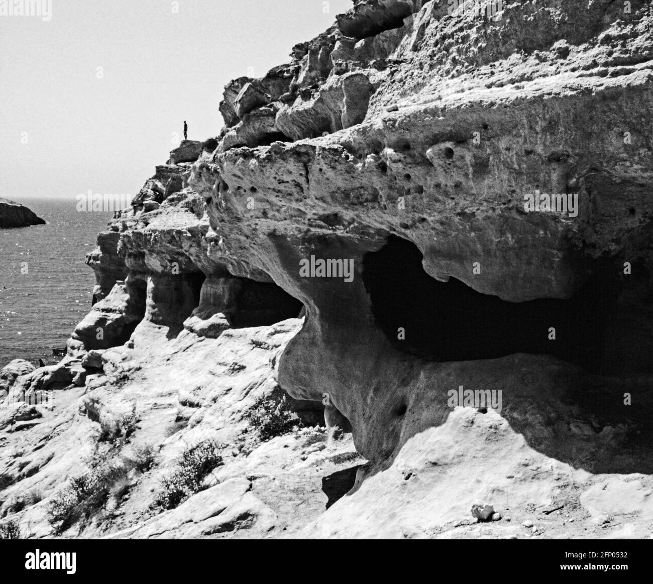 Archival monochrome image. View of the caves at Matala. Artificial caves created in the Neolithic time and used as graves in the Roman period followed Stock Photo