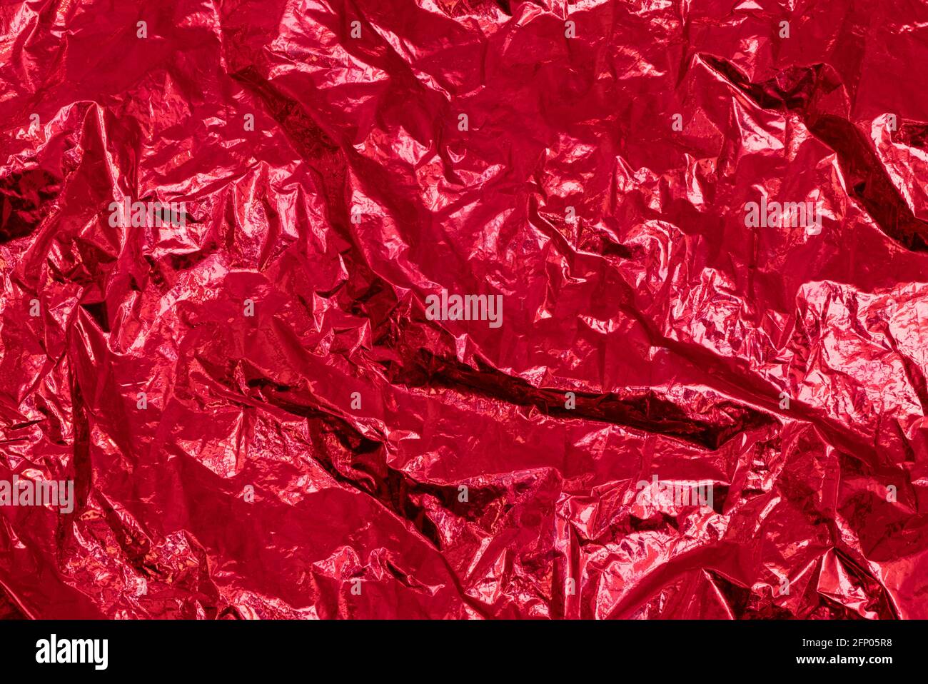 Wrinkled crumpled red metallic foil texture, abstract background Stock