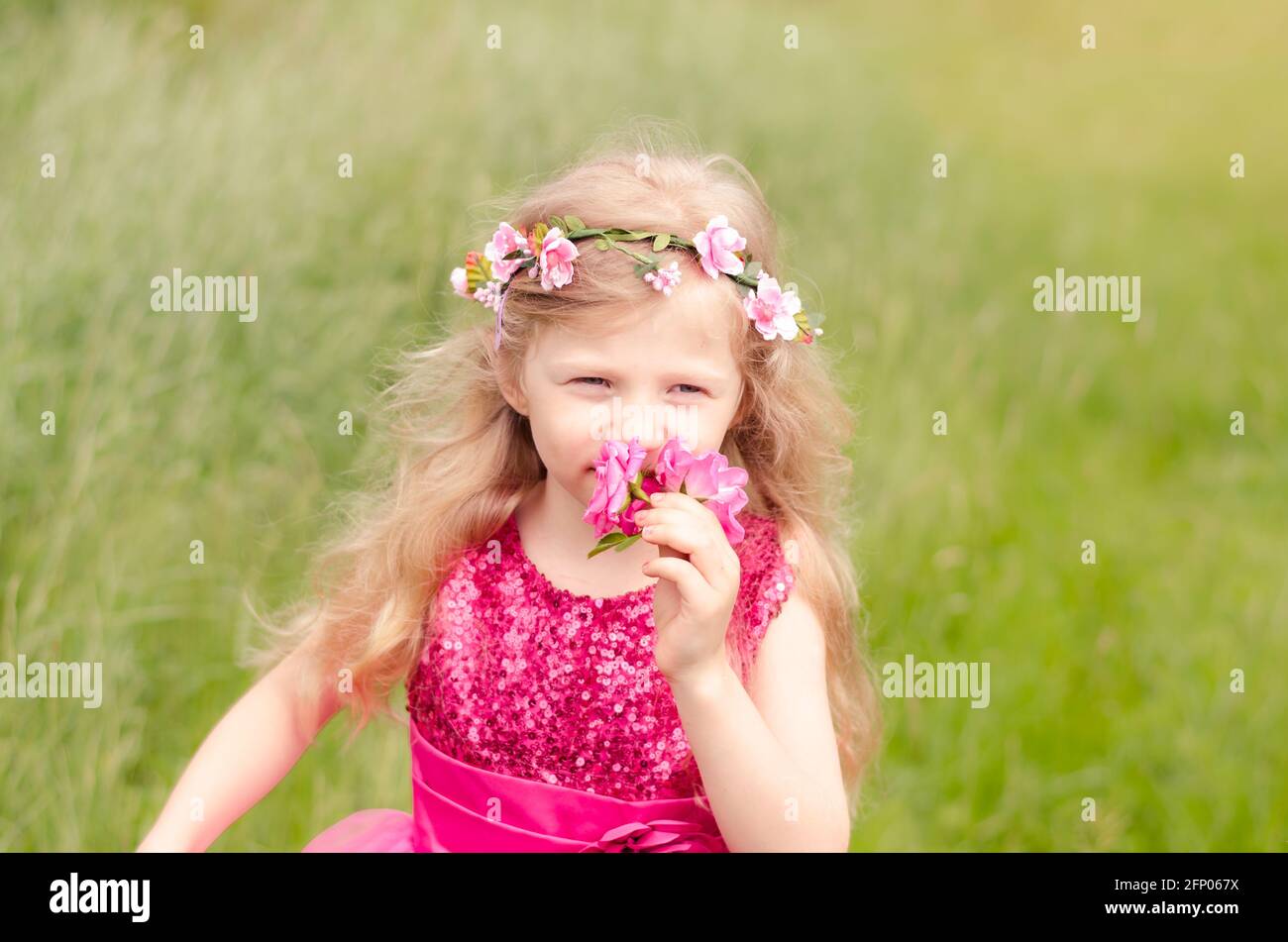 beautiful blond girl in pink dress holding pink rose flower Stock Photo