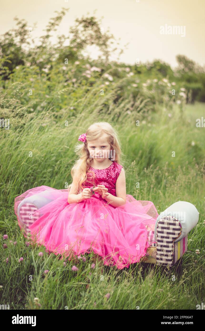 beautiful blond girl in pink dress in the meadow Stock Photo
